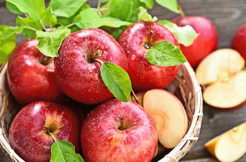 A basket of red Royal Gala apples on a table.