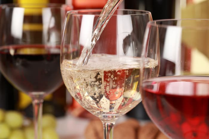 Closeup of three wine glasses with white wine being poured into the middle glass. Wine tastings are available at St. Croix Vineyards, the on-site winery at Aamodt's Apple Farm.