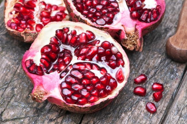 Closeup of cut pomegranate halves. Taste is ultimately the best method of how to tell if a pomegranate is ripe.