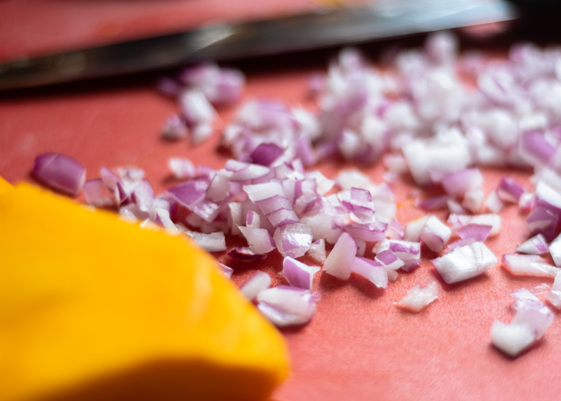 Closeup of chopped purple onion on a red cutting board.