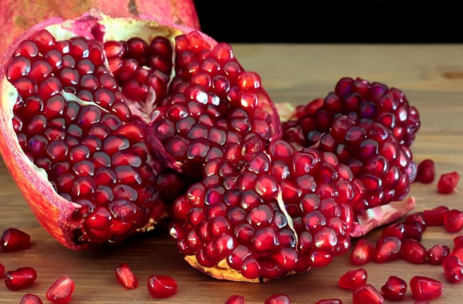 Closeup de uma romã aberta com muitos arils vermelhos e suculentos. Saber armazenar romãs significa que você pode desfrutar da fruta por semanas ou até meses.