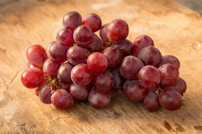 Bunch of red grapes on a wooden table.