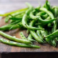 Closeup of green beans on a cutting board.